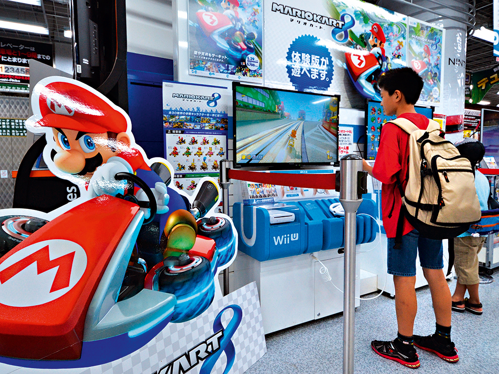 Customers play with Nintendo’s current video game console, the Wii U, at a display stand in Japan